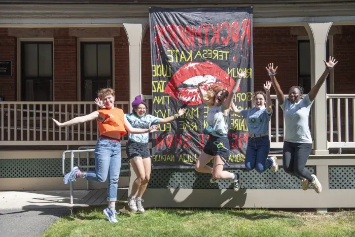 Residents of Morris House jump in front of their house banner for the year, which reads "Rocky Morris Picture Show"